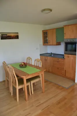 a kitchen with a wooden table with chairs and a table and a kitchen with at Apartma TiJa in Moravske Toplice