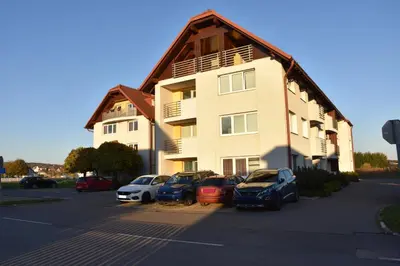 a building with cars parked in a parking lot at Apartma TiJa in Moravske Toplice
