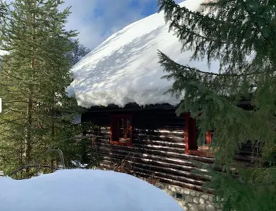 a snow covered log cabin with a snow covered roof at Mountain Dreams House - Stunning view over Lake Jasna! in Kranjska Gora