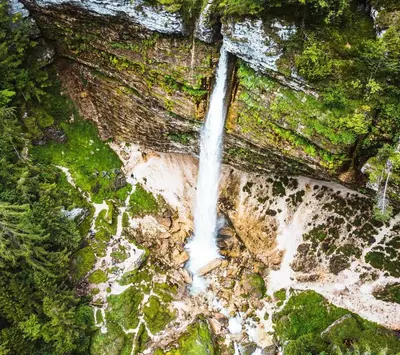 an aerial view of a waterfall on the side of a cliff at Nature Lover's Paradise in Julian Alps in Mojstrana