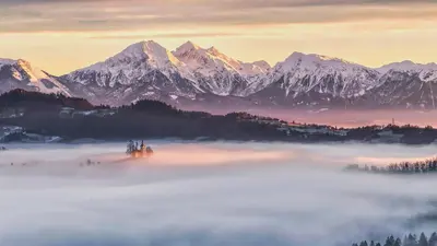 a foggy valley with snowy mountains in the background at Apartmaji Pr Smolet in Škofja Loka
