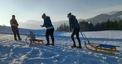 a group of people standing in the snow with a sled at Apartmaji Pr Smolet in Škofja Loka