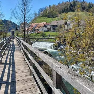 a wooden bridge over a river with a waterfall at Apartmaji Pr Smolet in Škofja Loka