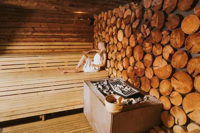 a woman sitting in a sauna with a stove at Hotel Toplice - Terme Krka in Smarjeske Toplice
