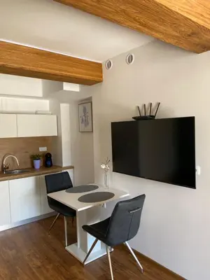 a kitchen with a table and chairs and a tv on the wall at Maximo Apartments - free parking in Maribor