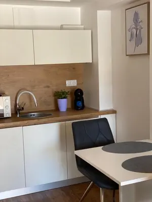 a kitchen with white cabinets and a sink and a table at Maximo Apartments - free parking in Maribor
