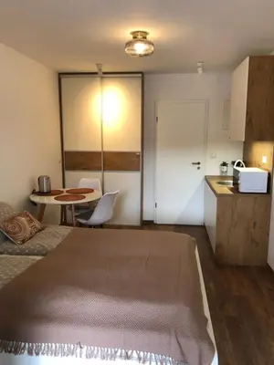 a bedroom with a bed and a table and a kitchen at Maximo Apartments - free parking in Maribor
