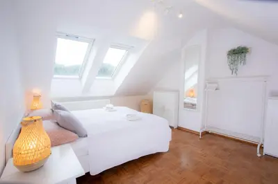 a white bedroom with a white bed and windows at Duplex Apartment Panj Kranjska Gora in Kranjska Gora