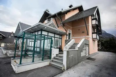 a house with glass doors and stairs in a parking lot at Duplex Apartment Panj Kranjska Gora in Kranjska Gora