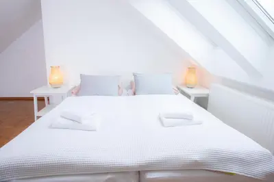 a white bedroom with a white bed and two tables at Duplex Apartment Panj Kranjska Gora in Kranjska Gora