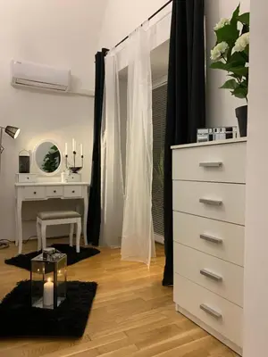a white bedroom with a dresser and a desk at Apartment Capital in Maribor