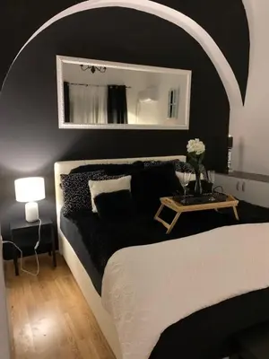 a bedroom with a black and white bed and a mirror at Apartment Capital in Maribor