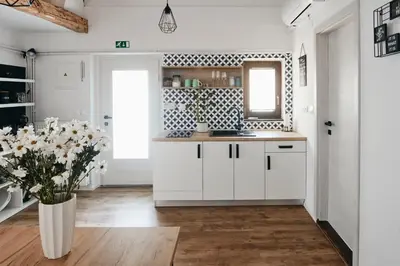 a kitchen with white cabinets and a vase of flowers at AVA HOUSE in Kranjska Gora