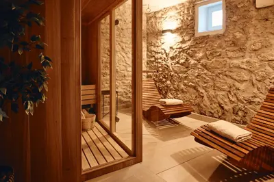 a bathroom with a mirror and a stone wall at AVA HOUSE in Kranjska Gora