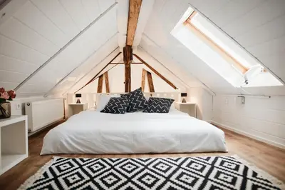 a bedroom with a white bed and a skylight at AVA HOUSE in Kranjska Gora