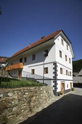 a large white house with a stone wall at Juvanova hiša (all house) in Luče