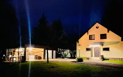 a large white building at night with a house at Vila Park Ravne in Ravne na Koroškem