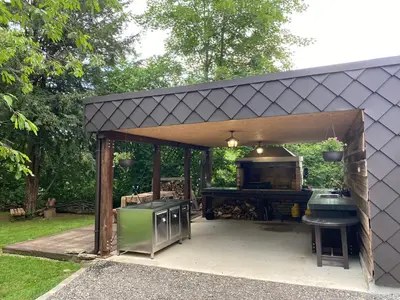 a barbecue pavilion in a garden with a grill at Vila Park Ravne in Ravne na Koroškem