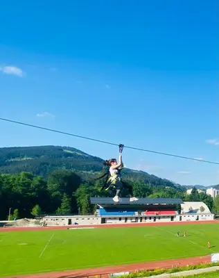 a woman is jumping in the air over a field at Vila Park Ravne in Ravne na Koroškem