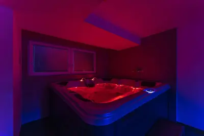 a bathroom with a tub with a red and blue lighting at Villa DonLeone in Ponikva