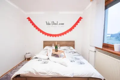 a bedroom with a bed with a red garland on the wall at Villa DonLeone in Ponikva