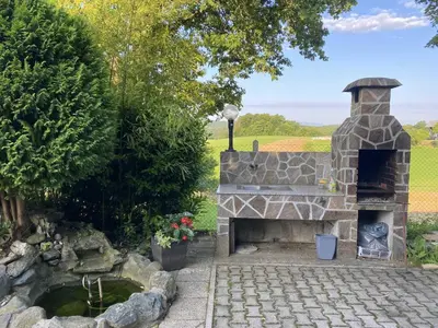 a stone fireplace in a garden with a pond at Villa DonLeone in Ponikva