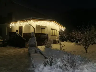 a house with christmas lights on it in the snow at Apartma Lana in Mojstrana
