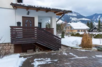a house with a deck in the snow at Apartma Lana in Mojstrana