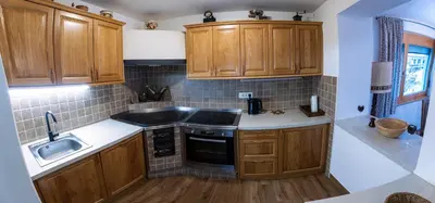 a small kitchen with wooden cabinets and a sink at Apartma Lana in Mojstrana