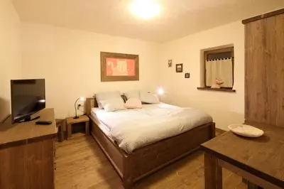 a bedroom with a bed and a desk and a television at Panonska Vas Apartments in Moravske Toplice