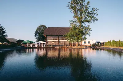 a building sitting next to a body of water at Panonska Vas Apartments in Moravske Toplice