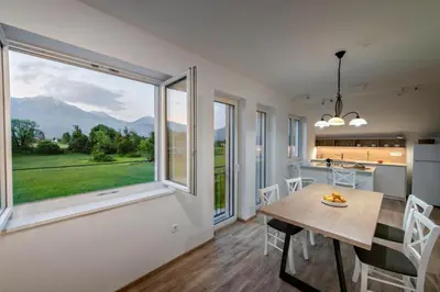 a kitchen and dining room with a table and a large window at Vila Vernig in Bled