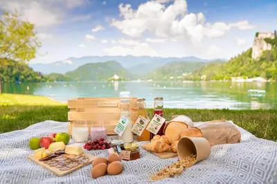 a picnic with food on a blanket next to a lake at Vila Vernig in Bled