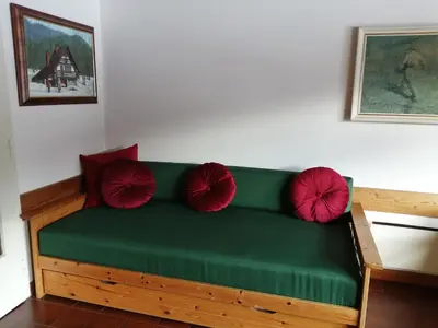 a green couch with red pillows in a room at House Nordika in Rateče