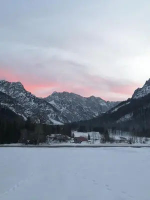 a snow covered lake with mountains in the background at House Nordika in Rateče