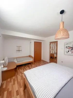 a white bedroom with a bed and a table at Lovely basement rental in Bled