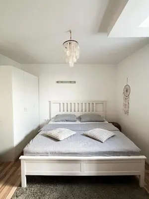 a bedroom with a white bed with a chandelier at Lovely basement rental in Bled