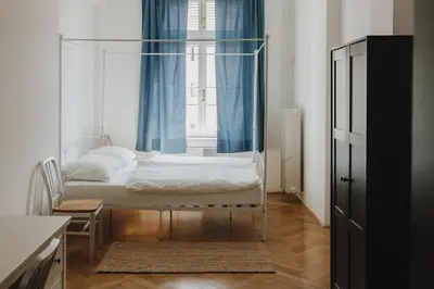 a bedroom with a bed and a window with blue curtains at Party Hostel Zzz in Ljubljana
