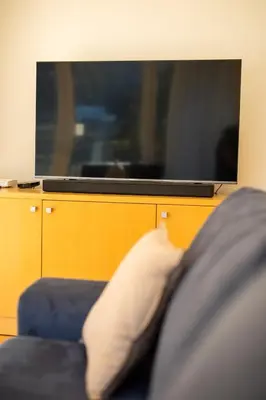 a blue couch with a white pillow in front of a tv at Pohorje Fox duplex apartment in Maribor