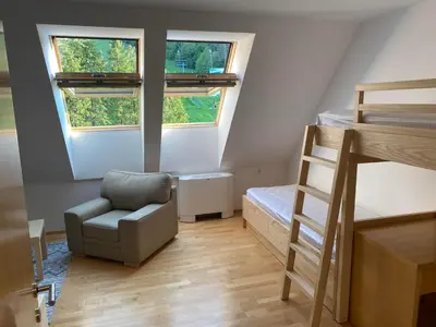 a small room with a chair and a bunk bed at Pohorje Fox duplex apartment in Maribor