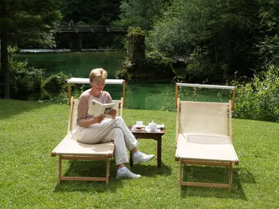 a woman sitting in a chair reading a book at Vila Park B&B - Adults Only in Bohinj