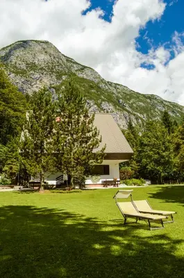 a park bench in front of a building with a mountain at Vila Park B&B - Adults Only in Bohinj