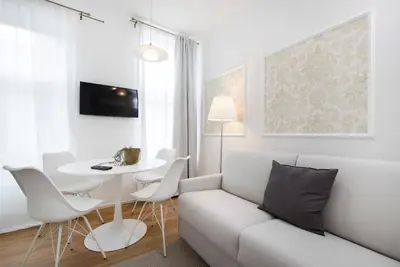 a white living room with a couch and a table at Cozy apartments in Ljubljana