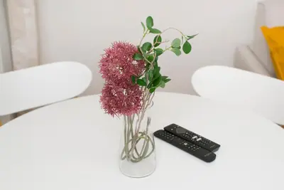 a vase with purple flowers and a remote control on a table at Cozy apartments in Ljubljana