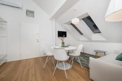 a white living room with a white table and chairs at Cozy apartments in Ljubljana
