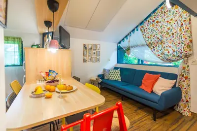a living room with a table and a blue couch at Boho House 4 camp Terme Catez with promotional tickets prices in Čatež ob Savi