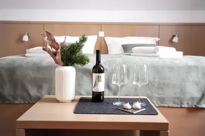 a bottle of wine on a table with two wine glasses at Hotel Pino Alpino in Kranjska Gora