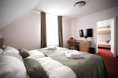 a bedroom with a large white bed and a television at Hotel Pino Alpino in Kranjska Gora
