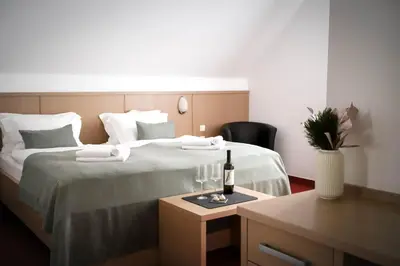 a hotel room with a bed with a bottle of wine on it at Hotel Pino Alpino in Kranjska Gora