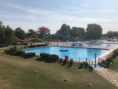 a large swimming pool in a park with a roller coaster at Spa Cottage Lavender in Terme Čatež in Čatež ob Savi